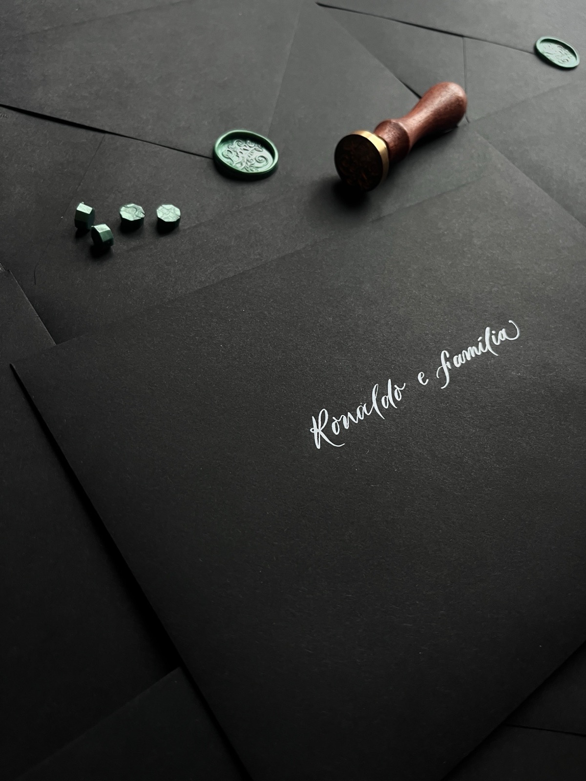 Hand-lettered wedding envelope suite in white calligraphy on black paper with green wax seals